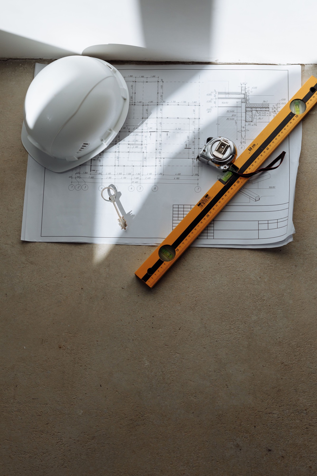 Casque de chantier, niveau et mètre ruban posés sur un plan d'exécution